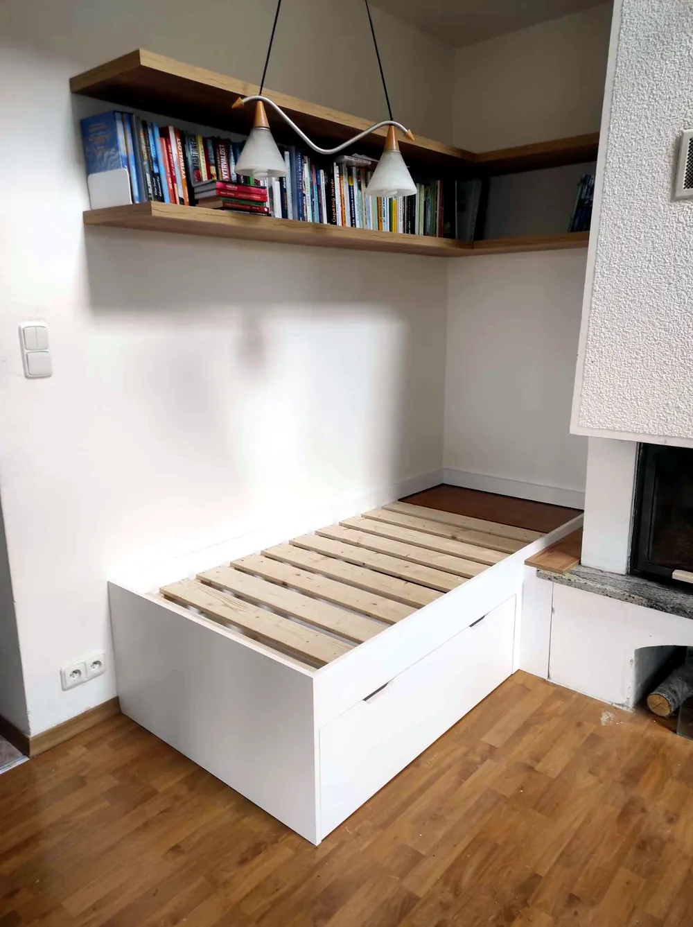 Postel s úložným prostorem a policemi nad ní