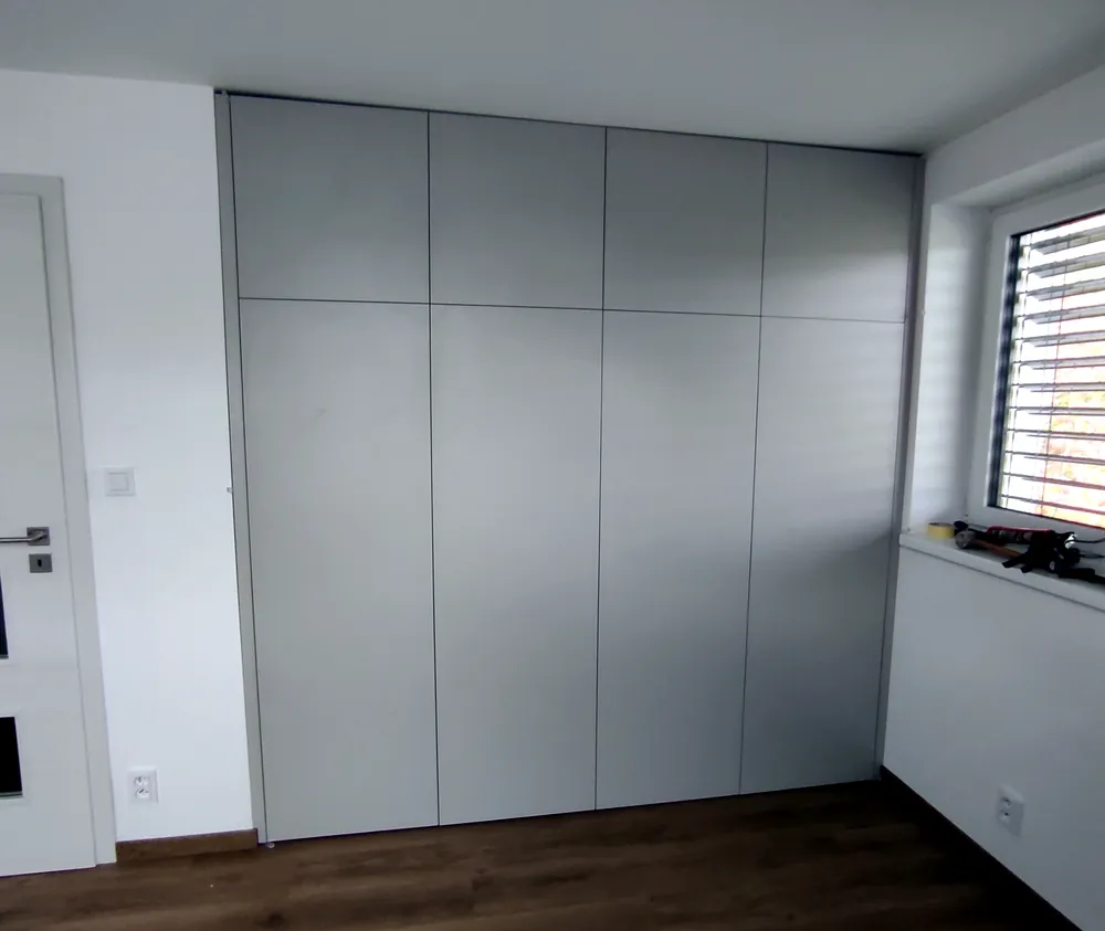 Šedá vestavná skříň přes celou stěnu